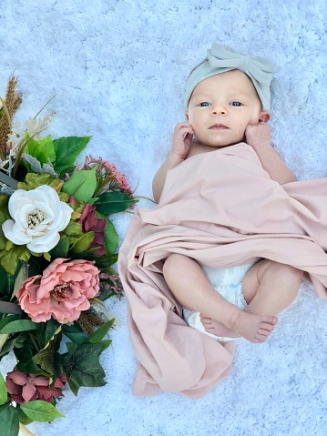 A newborn baby and a flower bouquet in the foreground