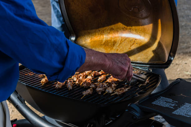 istock Man hands preparing chicken on outdoors grill 1454349262