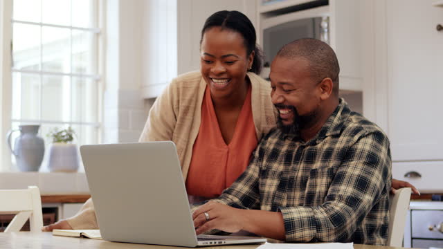 Happy young husband and wife using  laptop