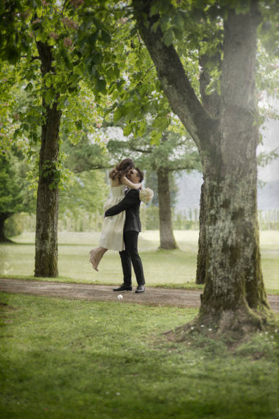 istock Bride and groom embracing in treelined path 1454351452