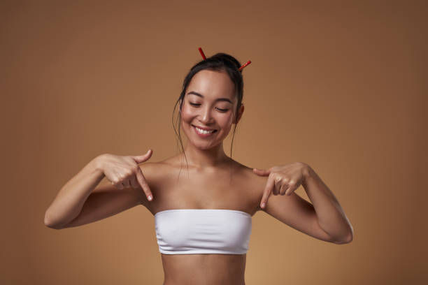 istock Asian girl pointing with fingers and looking down 1454354482