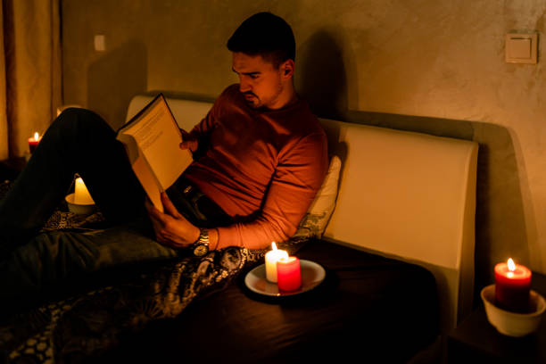 istock A young man is suffering an electricity crisis at home and reading a book. 1454358095