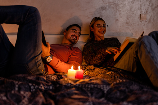 During an energetic crisis, a young couple is reading books in the dark with lit candles.