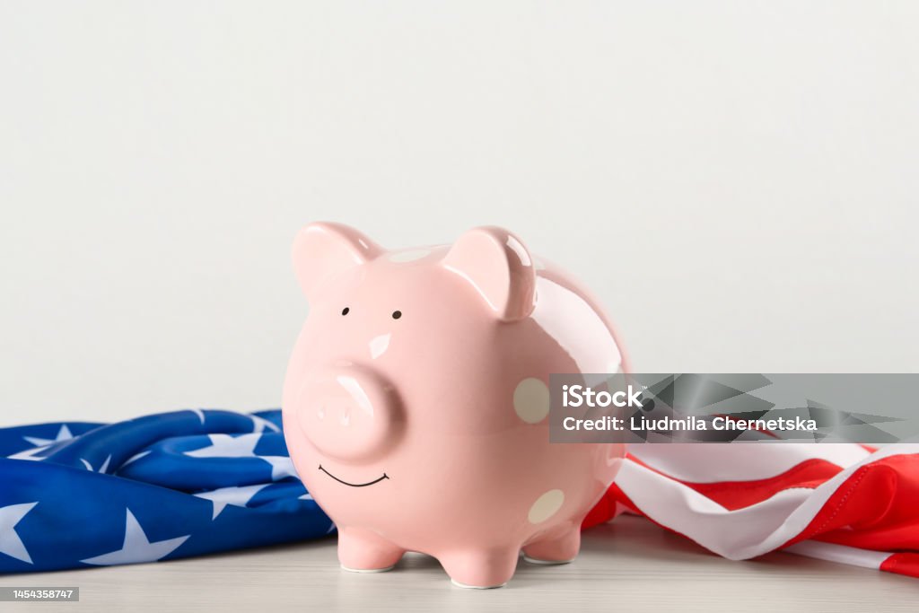 Piggy bank and American flag on white wooden table American Flag Stock Photo