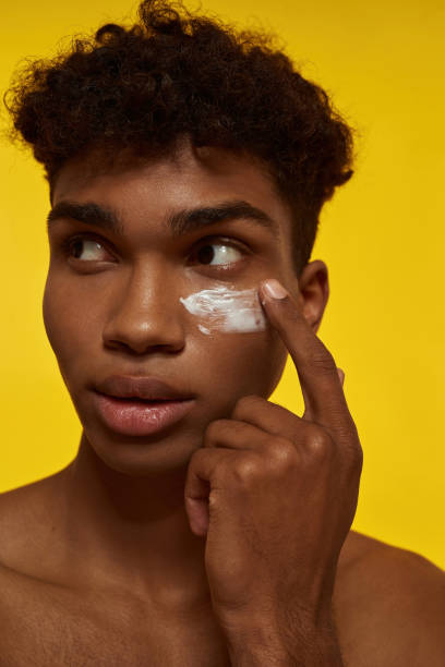 istock Concentrated guy smearing cosmetic cream on face 1454360073