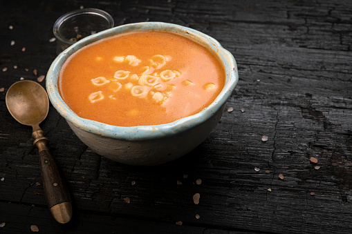 Tomato soup on dark table with space