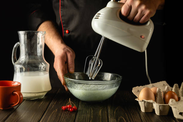 istock Cooking an egg omelette with milk using an electric hand mixer. Delicious breakfast by the hands of the chef in the kitchen 1454361105