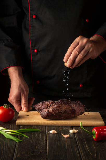 istock The chef sprinkles the baked beef meat with salt. Work environment on the kitchen table. Asian cuisine. 1454361209