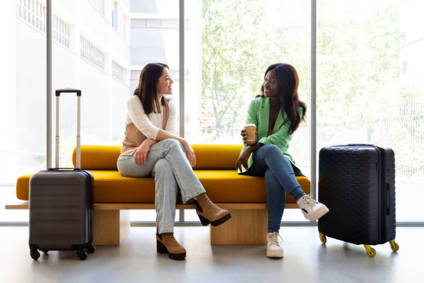 istock Multiracial young women sitting on hotel reception bench talking. 1454361399