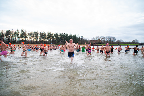 oldenzaal, netherlands - january 1, 2023: People running into the water at the traditional new years dive