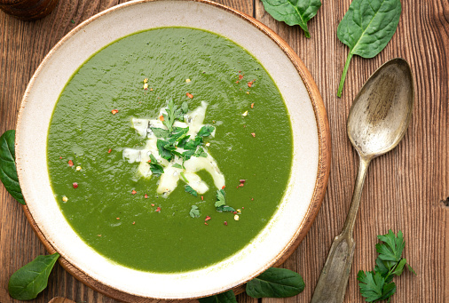 Top view of Spinach soup with spoon on wooden table.