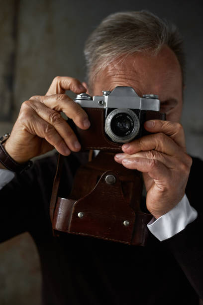 istock Partial of grey hair man take photo on old camera 1454363210