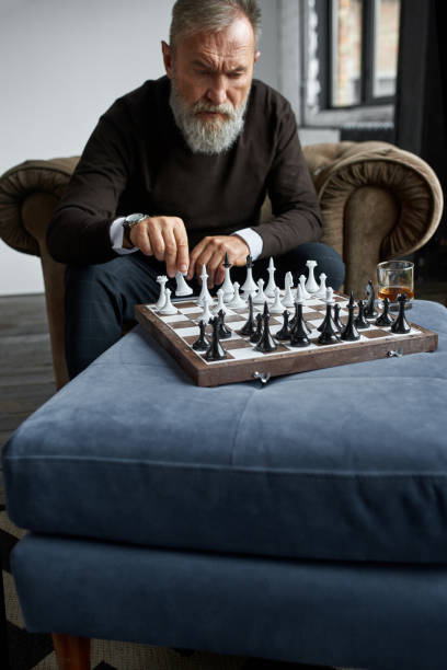 istock Grey hair thoughtful man playing chess at home 1454363496