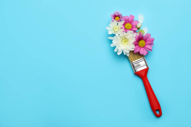 istock Brush painting with chrysanthemum flowers on light blue background, top view. Space for text. Creative concept 1454364490