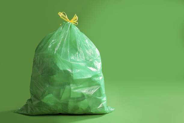 Trash bag full of garbage on green background. Space for text