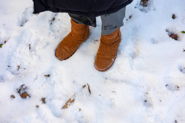 istock Woman's boots on the snow beside footprints 1454368515