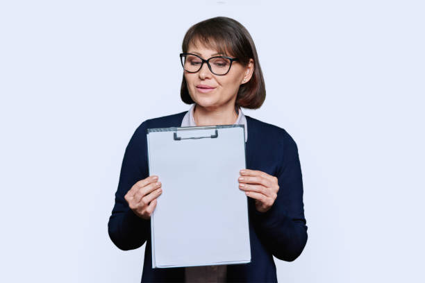 istock Business woman pointing at blank space, holding clipboard, white background 1454371285