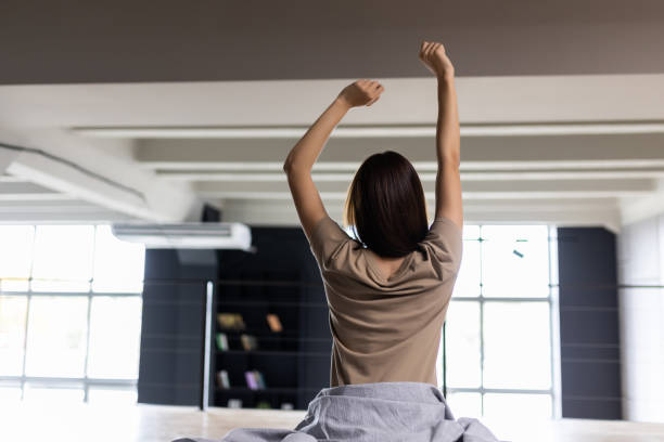 istock Young Woman stretching in bed after waking up, back view 1454371477