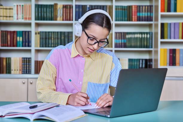 istock Teenage girl student studying in library, using laptop 1454371601