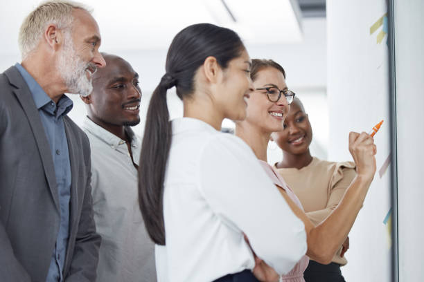 istock Teamwork, collaboration and business people with sticky notes in office brainstorming on moodboard, storyboard or glass wall. Work team, people or staff writing or planning together on vision board. 1454372012