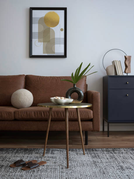 istock Interior design of harmonized living room with brown sofa, blue commode, coffee table, mock up poster frame, decoration, carpet and personal accessories. Stylish home decor. Template. 1454373054