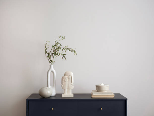 istock Minimalist composition of elegant and outstanding space with copy space, navy commode, green leaves in vase books, sculpture and personal accessories. Home decor. Template. 1454373123