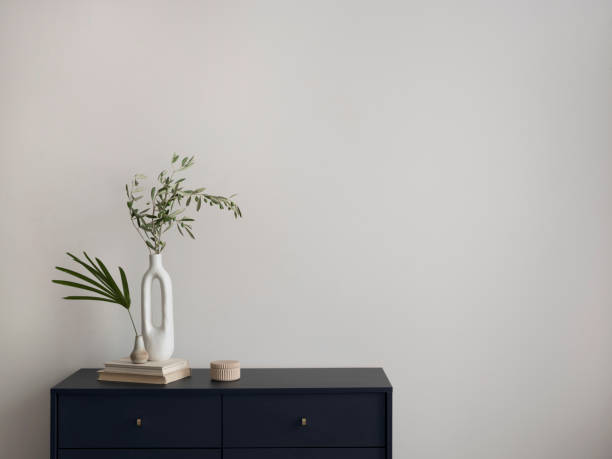 istock Minimalist composition of elegant and outstanding space with copy space, blue commode, books, green leaves in vase and personal accessories. Home decor. Template. 1454373146