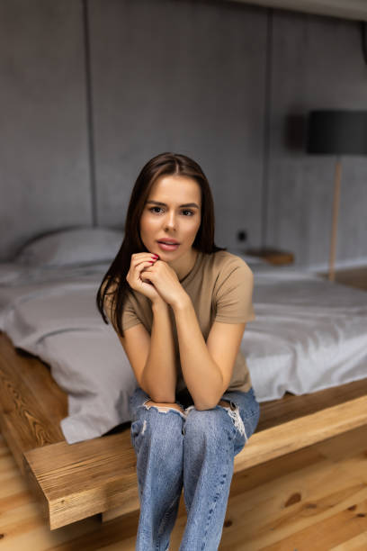 istock Young pretty beautiful woman sitting on bed at home 1454374213