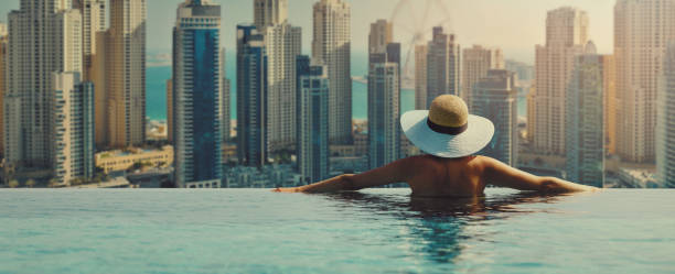 woman enjoying Dubai marina skyline from luxury hotel infinity pool. banner with copy space stock photo