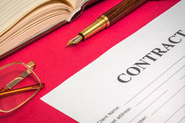 istock Office still life on red table with gilded pen, notepad and a contrsct is preparing for the notes 1454377468