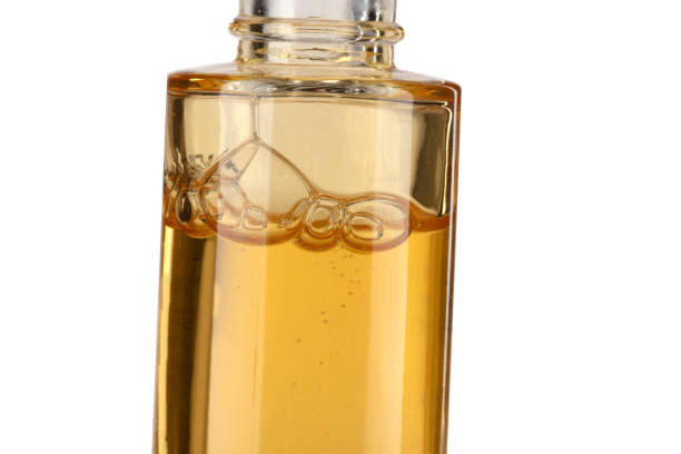 Part of a bottle with yellow cosmetic liquid close-up on a white background.