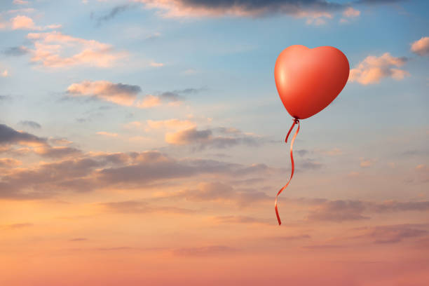 Heart shaped bred balloon on colorful clouds sunset sky. This file is cleaned and retouched.