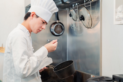 A male chef tasting food in the kitchen
