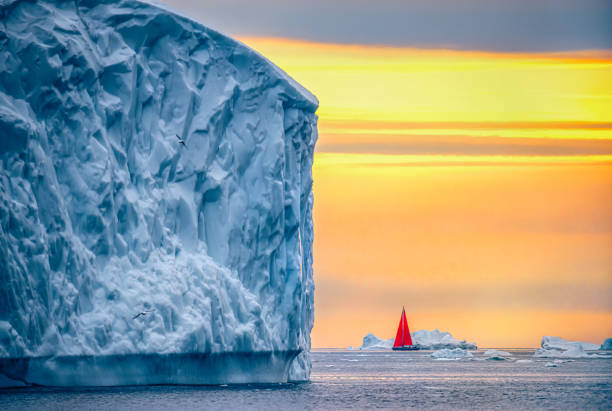 hermoso paisaje con grandes icebergs y barco rojo - sol de medianoche fotografías e imágenes de stock