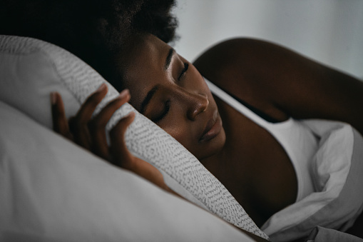Side view of beautiful young Afro American woman smiling while sleeping in her bed at home