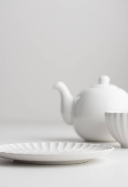 istock White clean empty tableware: plate and teapot on white background for a dessert 1454381946