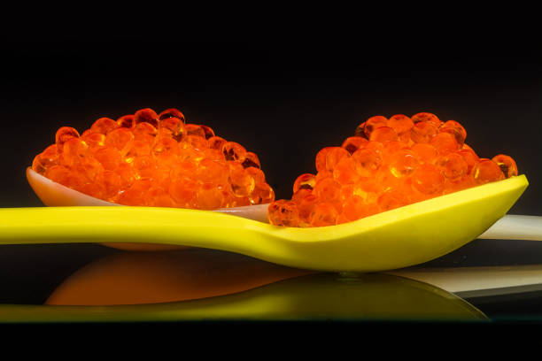 A hill of red salmon caviar in a large wooden spoon on a white background. isolated object