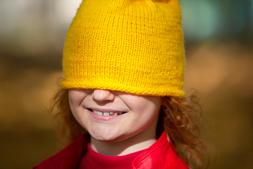 The little girl pulled a yellow knitted hat over her eyes. Fall has come.
