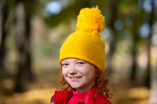 Portrait of a beautiful preschool girl in a red beret. Walk in the autumn season.