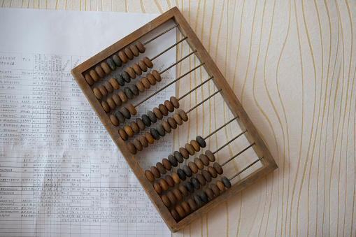 Vintage wooden abacus on the background of a sheet with numbers and calculations.