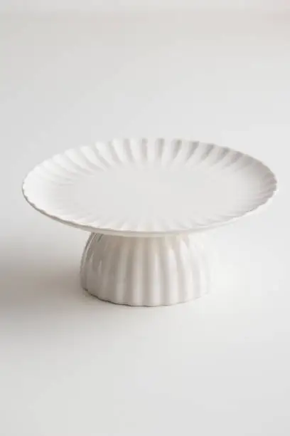 Empty tableware - white plate cakestand on white table as a background for a dessert vertical photo with a copy space