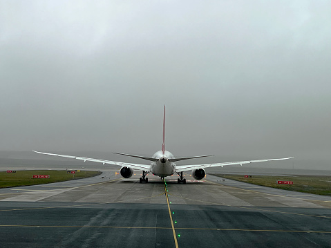 View from the window of a passenger plane on a part of the wing and pouring rain from a cloud against the background of elevated fields