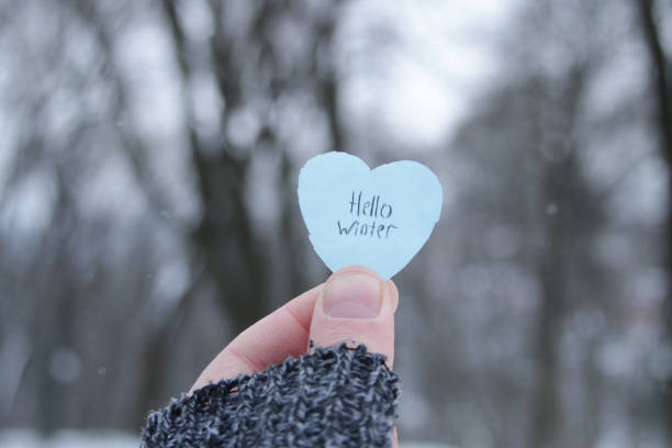 Hello winter. Hand holds a blue heart with the inscription. stock photo