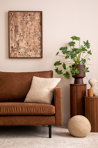 Modern composition of living room interior with mock up poster frame, brown sofa, beige coffee table, decoration, pillow and personal accessories. Home decor. Template.