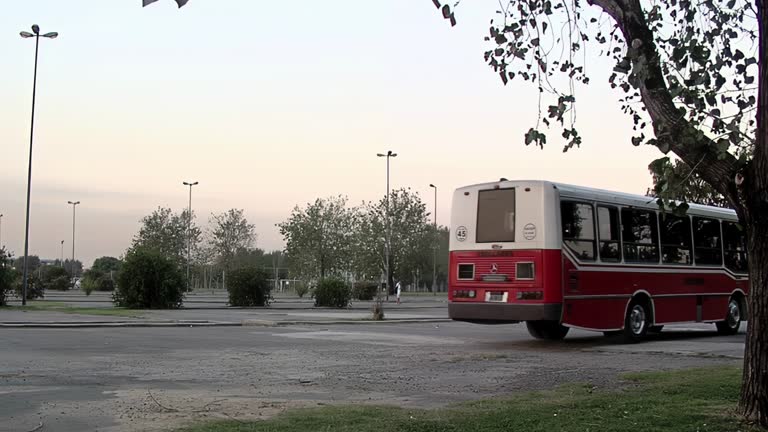 A Red and White School Bus Leaving a Sports Field in Buenos Aires, Argentina.