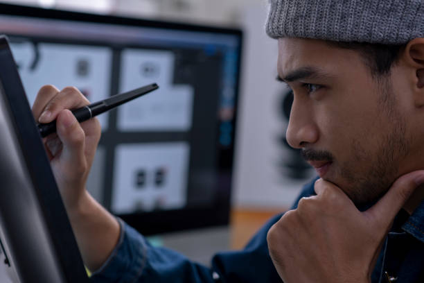 istock Young Asian male designer drawing on digital tablet. 1454390889
