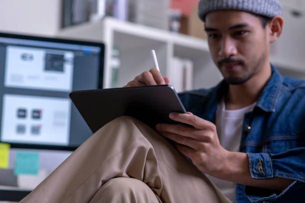 istock Young Asian male designer drawing on digital tablet. 1454390925