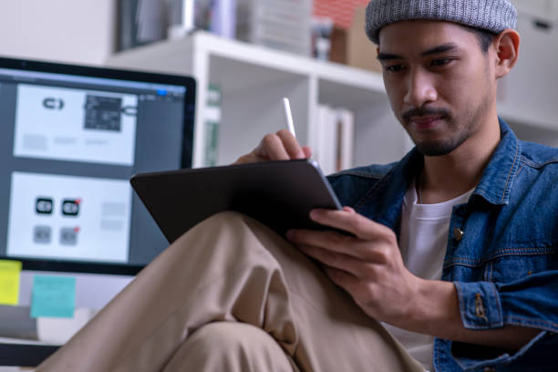 istock Young Asian male designer drawing on digital tablet. 1454390977