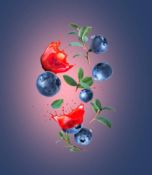 Whole and sliced blueberries with juice splashes in the air on a blue background