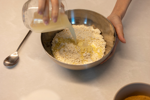 Making hotteok dough before baking, pouring yeast water and mixture into a paste by hands